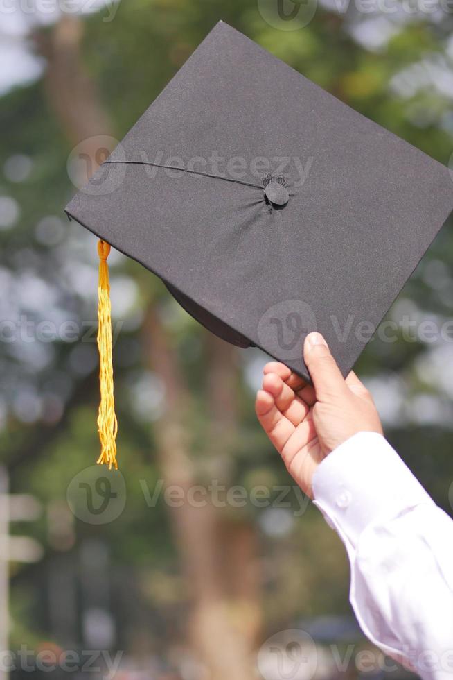 Student hold hats in hand during commencement success on yellow background photo
