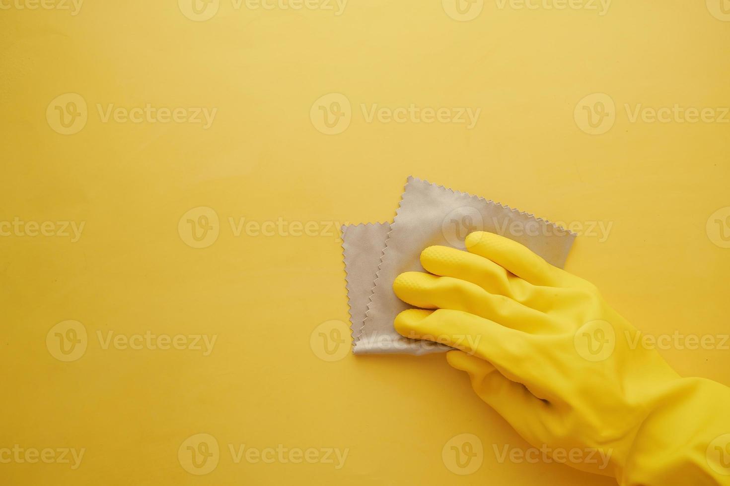 hand in yellow rubber gloves cleaning yellow flat background photo