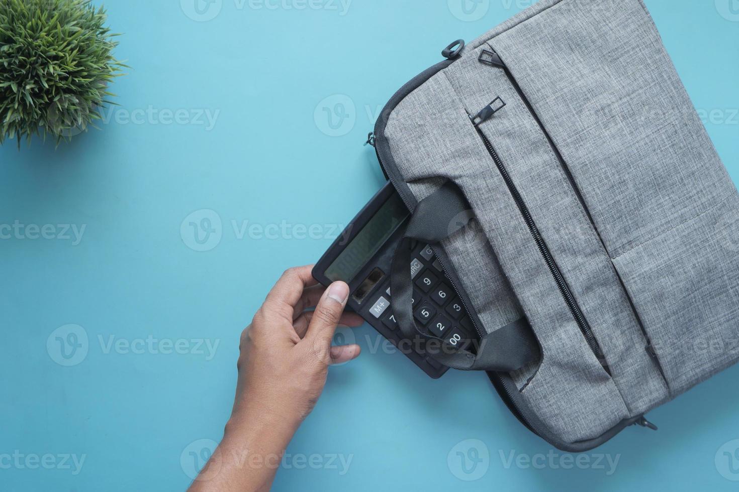 top view of young man putting office stationary in his bag photo