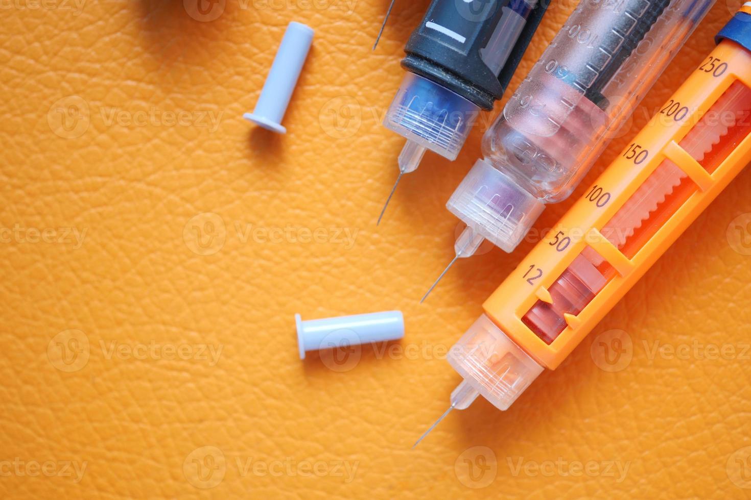 Insulin pens on orange background photo