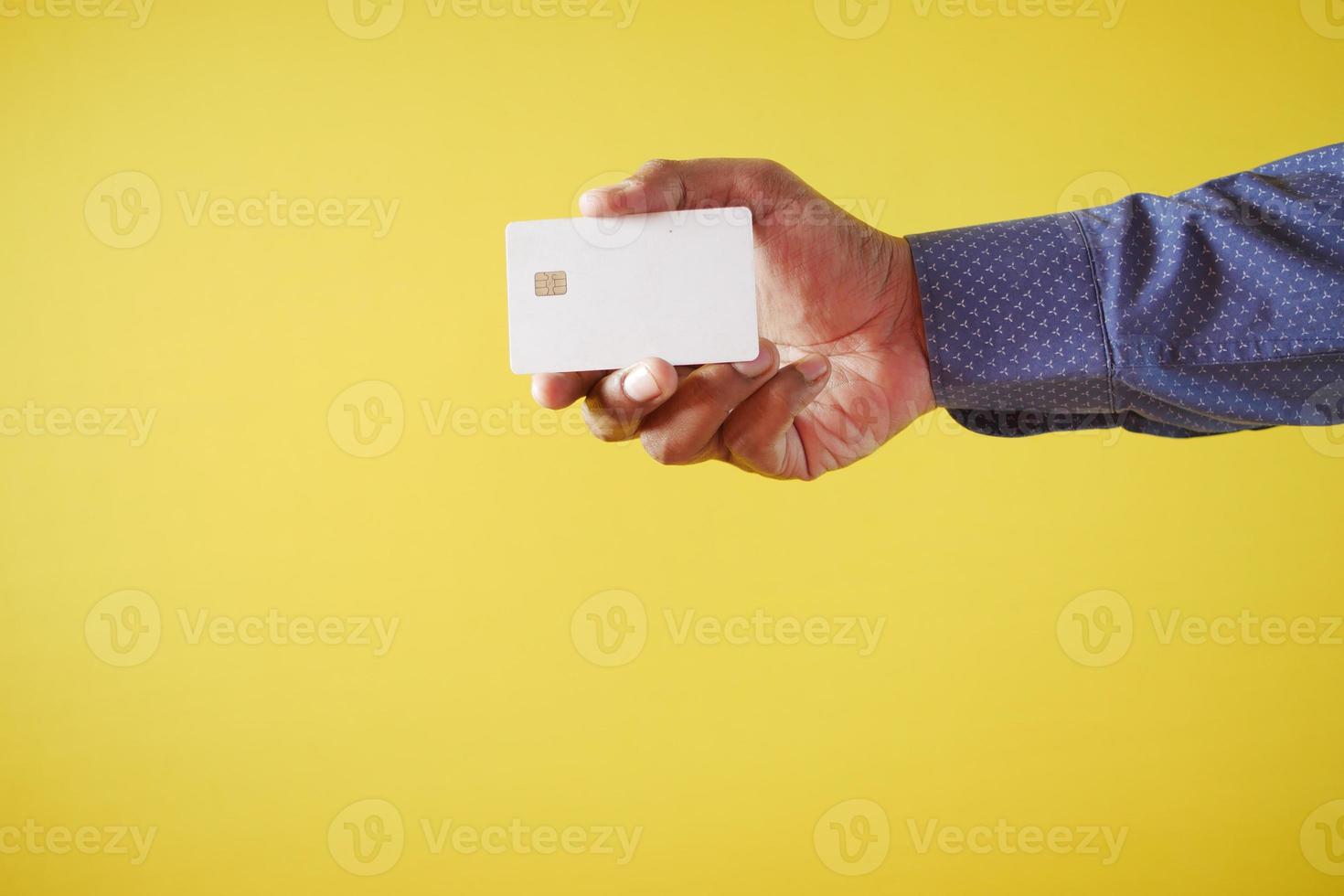 person hand holding credit card against yellow background photo