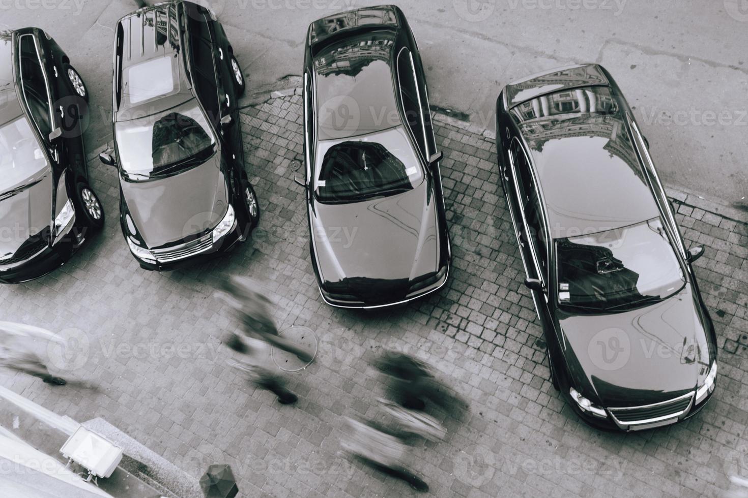 parked cars in the city and people walking near them are blurred. photo