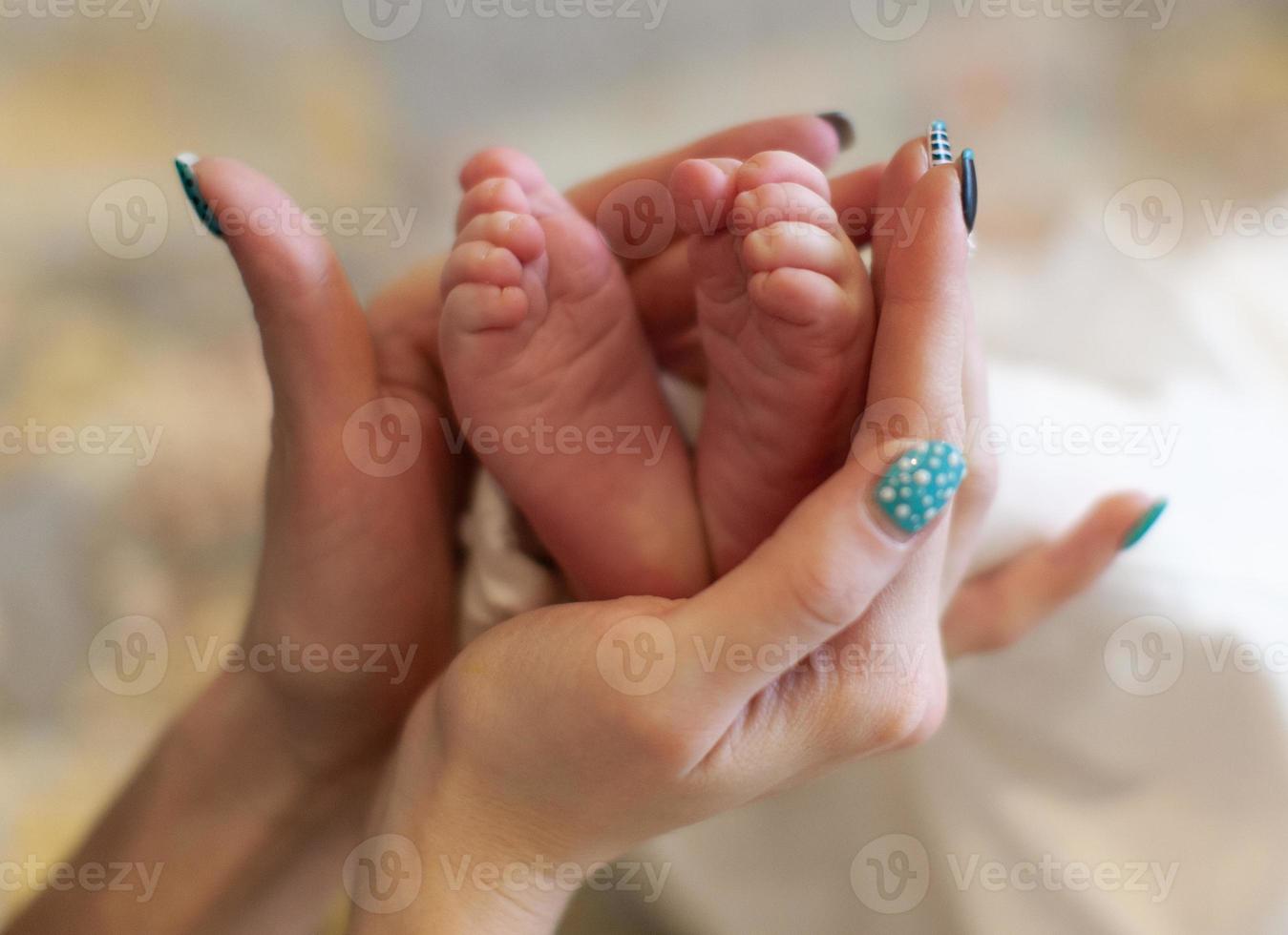 primer plano de las manos de la madre y los pies pequeños del bebé. foto