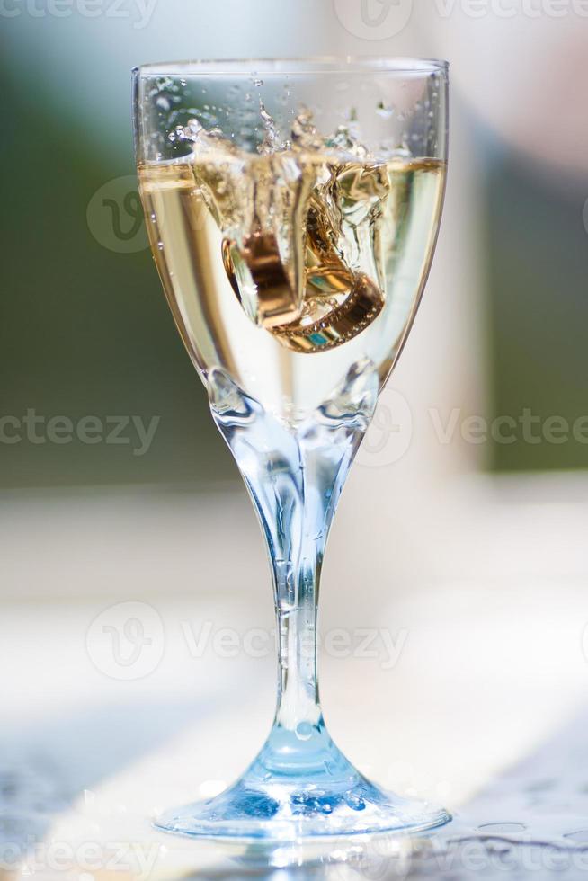 close up of wedding rings falling into a glass of champagne photo