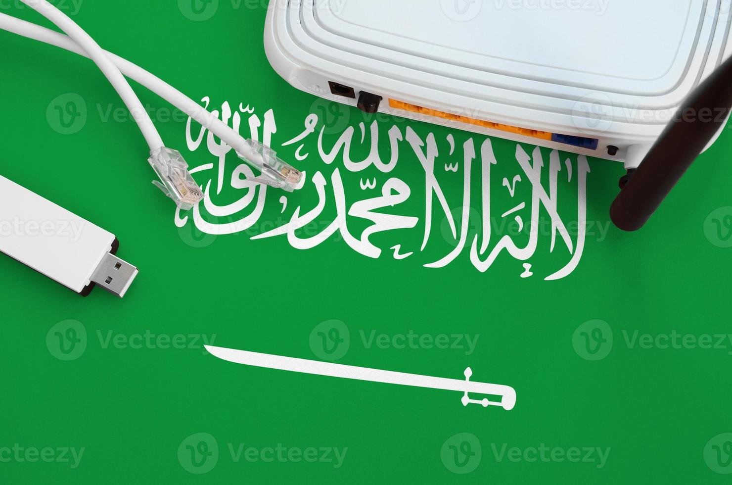 Saudi Arabia flag depicted on table with internet rj45 cable, wireless usb wifi adapter and router. Internet connection concept photo