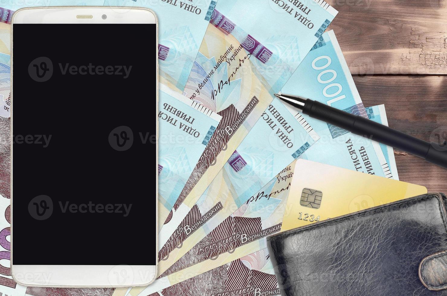 1000 Ukrainian hryvnias bills and smartphone with purse and credit card. E-payments or e-commerce concept. Online shopping and business with portable devices photo