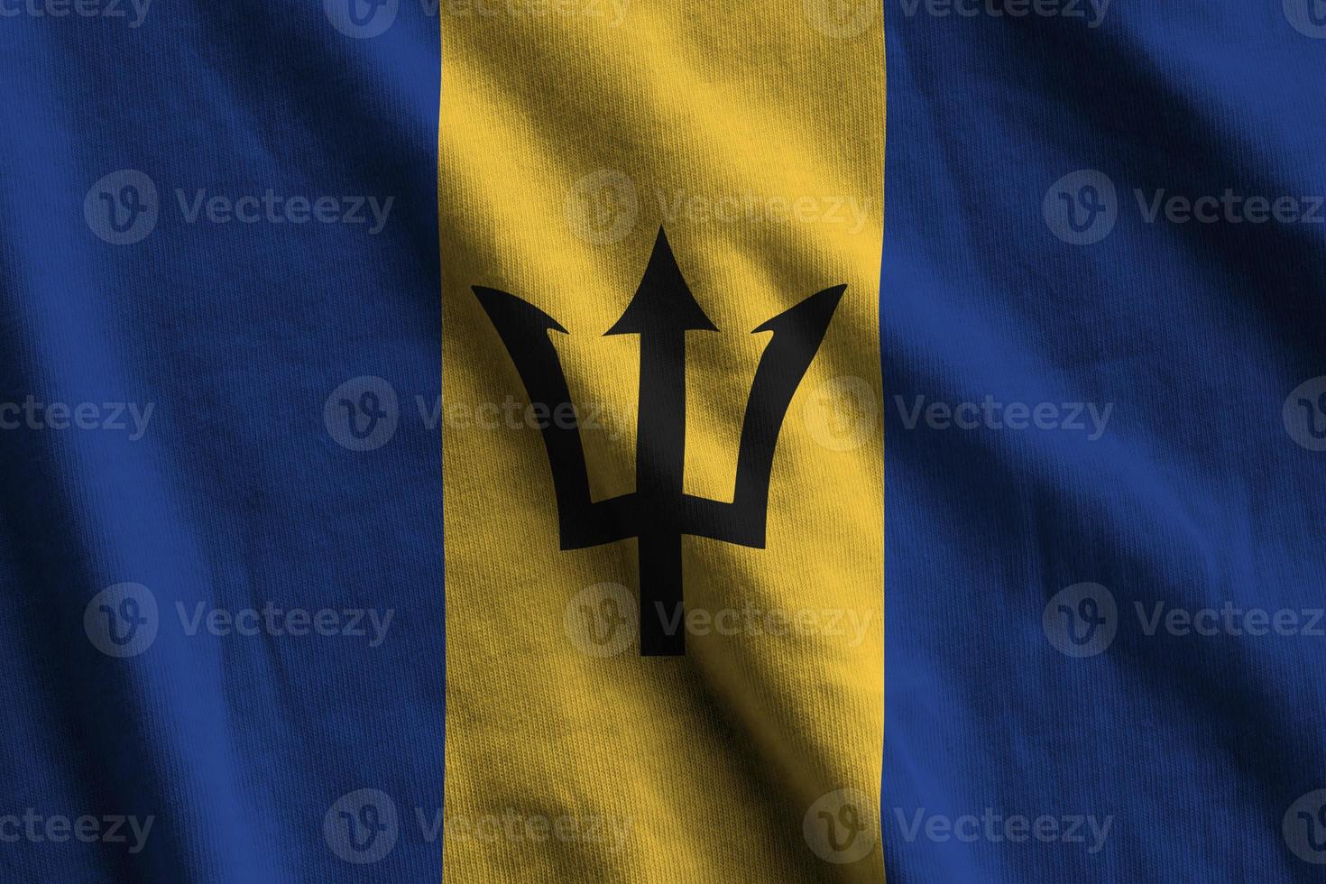 Barbados flag with big folds waving close up under the studio light indoors. The official symbols and colors in banner photo