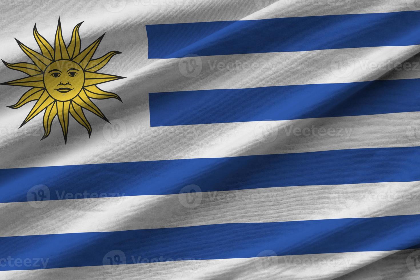 Uruguay flag with big folds waving close up under the studio light indoors. The official symbols and colors in banner photo