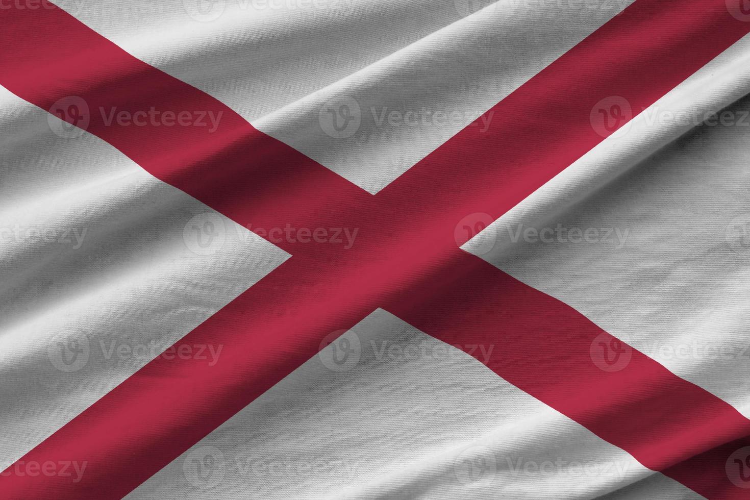 alabama bandera del estado de estados unidos con grandes pliegues ondeando de cerca bajo la luz del estudio en el interior. los símbolos y colores oficiales en banner foto