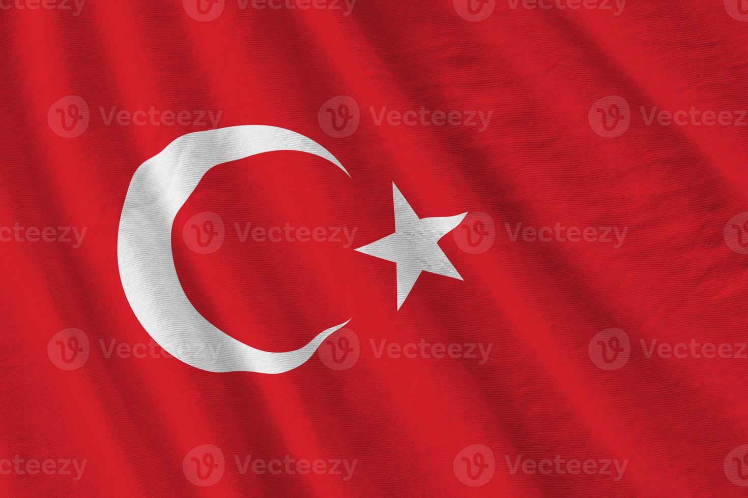 Turkey flag with big folds waving close up under the studio light indoors. The official symbols and colors in banner photo