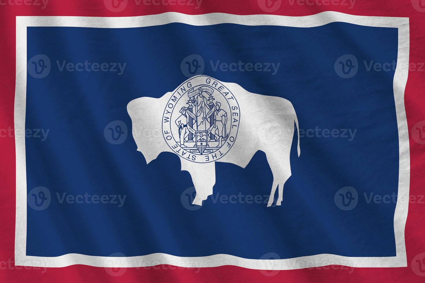 Wyoming US state flag with big folds waving close up under the studio light indoors. The official symbols and colors in banner photo
