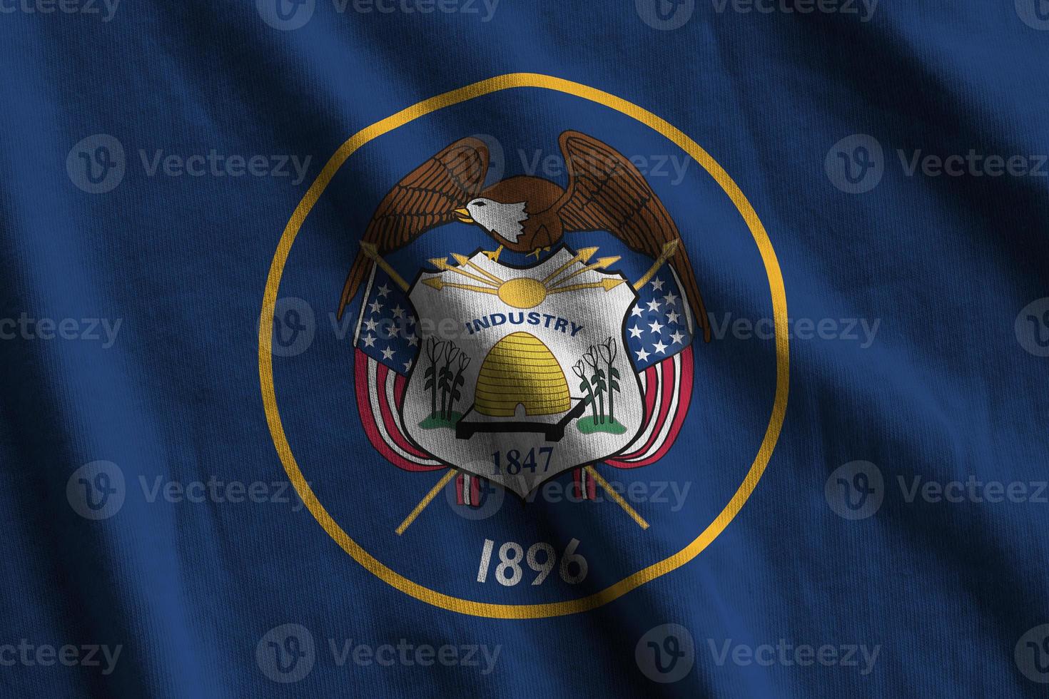 Utah US state flag with big folds waving close up under the studio light indoors. The official symbols and colors in banner photo