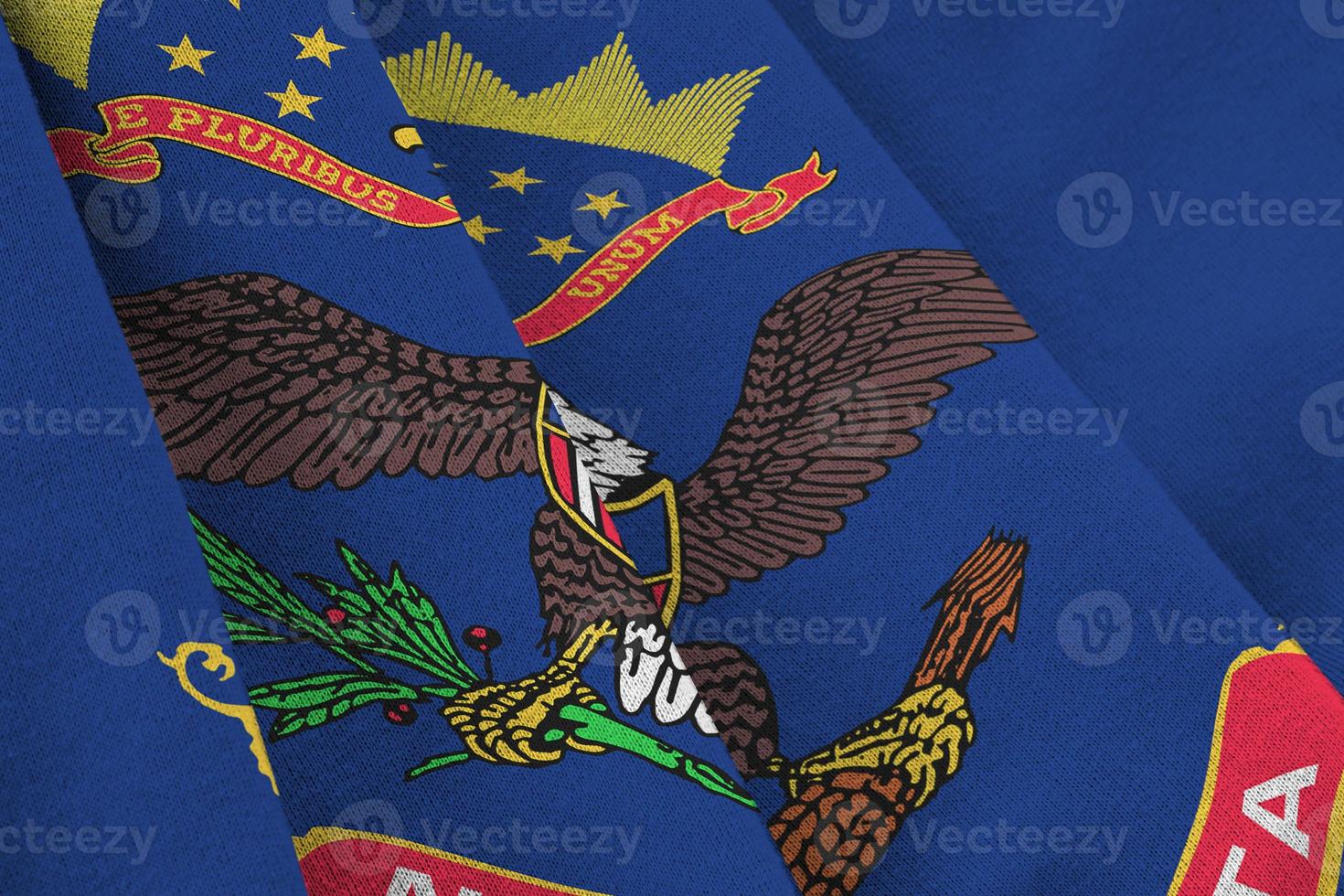North Dakota US state flag with big folds waving close up under the studio light indoors. The official symbols and colors in banner photo