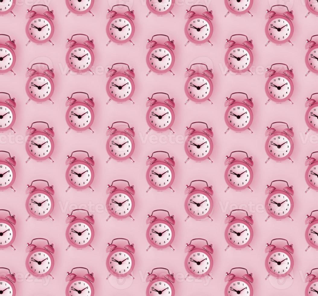 Wasting time concept. Many coral red alarm clock Image toned in Viva Magenta, color of the 2023 year photo