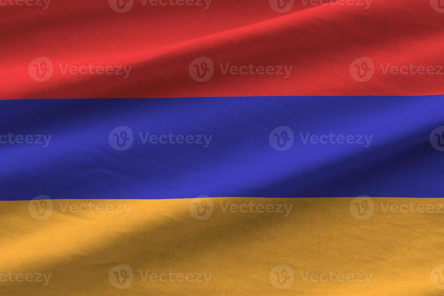 Armenia flag with big folds waving close up under the studio light indoors. The official symbols and colors in banner photo