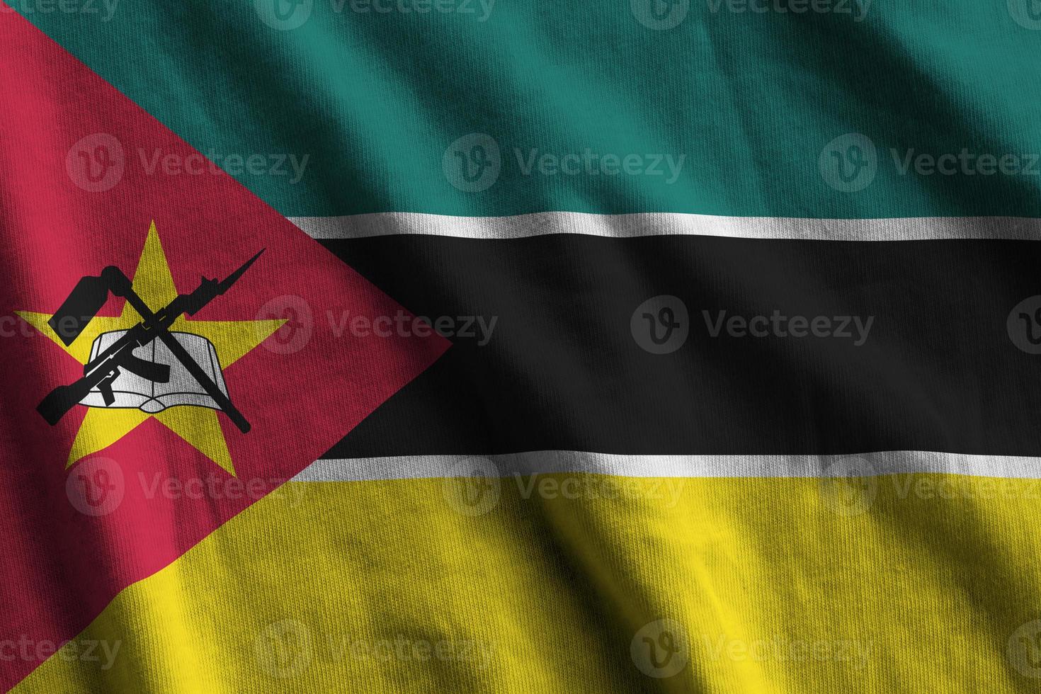 bandera de mozambique con grandes pliegues ondeando de cerca bajo la luz del estudio en el interior. los símbolos y colores oficiales en banner foto