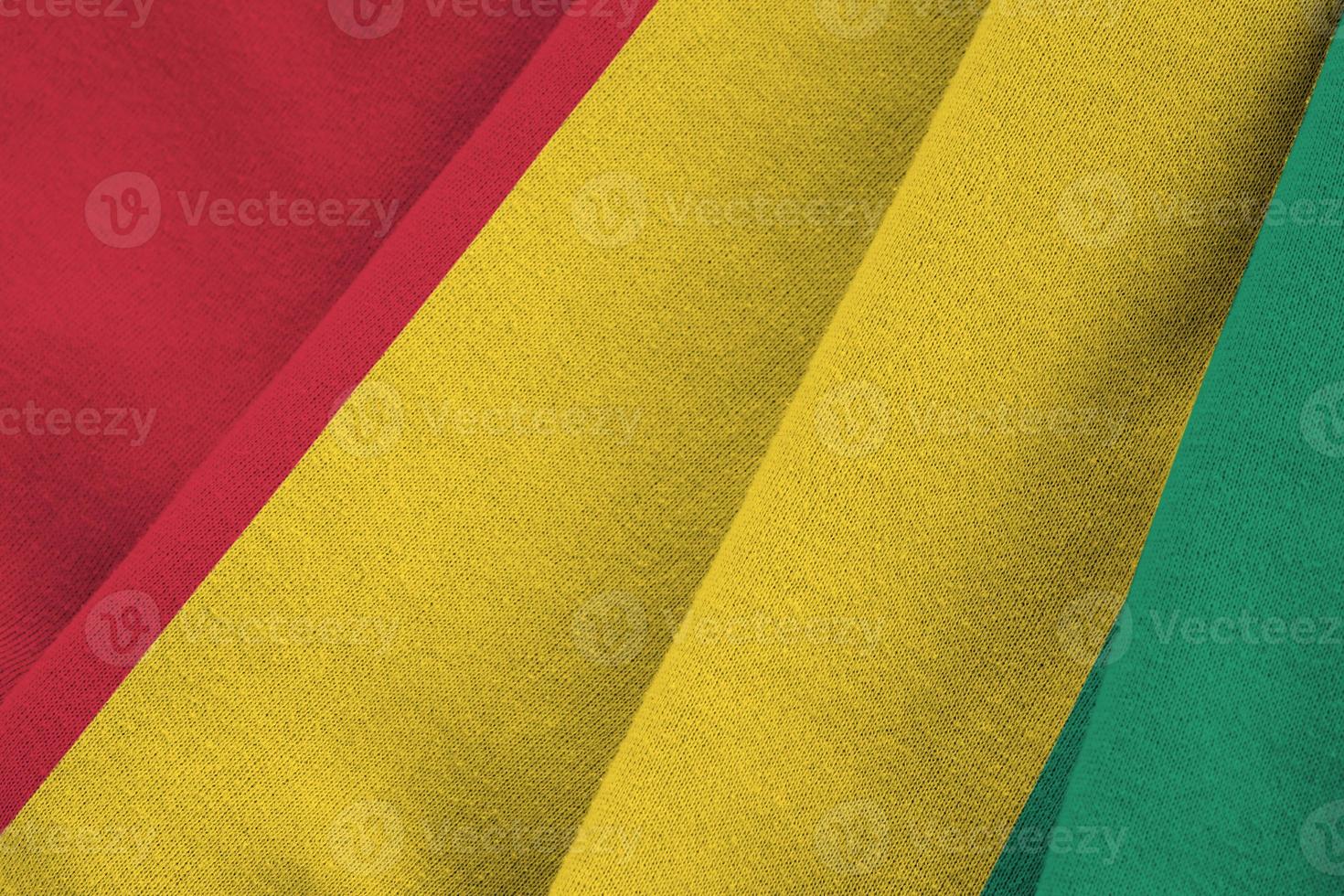 Guinea flag with big folds waving close up under the studio light indoors. The official symbols and colors in banner photo