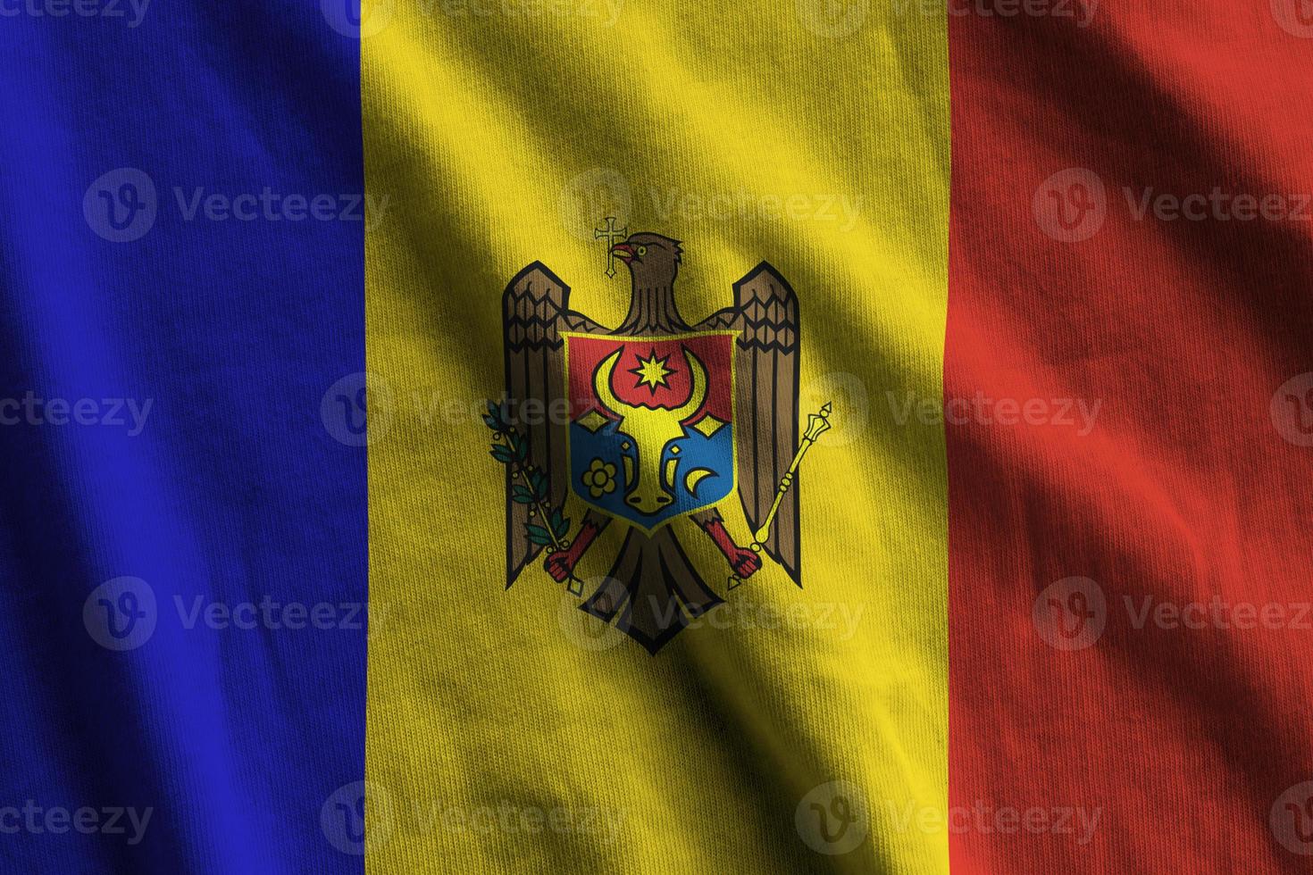 Moldova flag with big folds waving close up under the studio light indoors. The official symbols and colors in banner photo