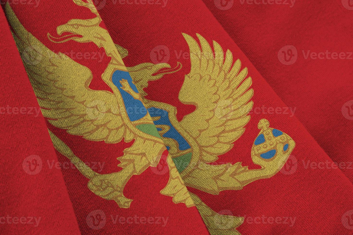 Montenegro flag with big folds waving close up under the studio light indoors. The official symbols and colors in banner photo