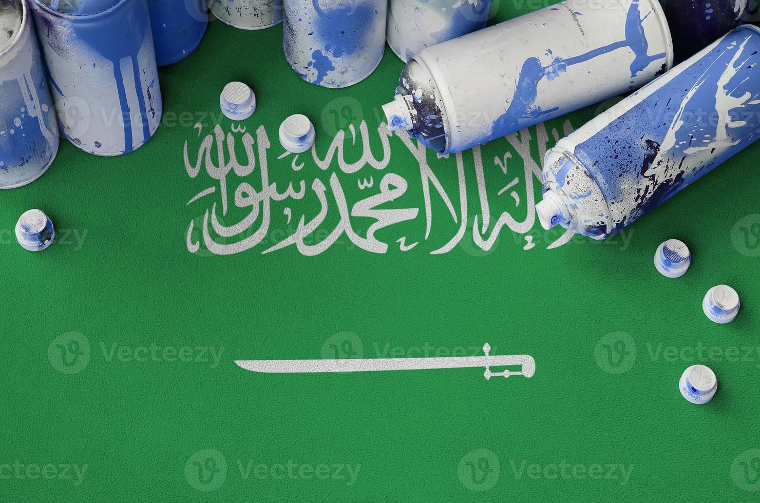 bandera de arabia saudita y pocas latas de aerosol usadas para pintar graffiti. concepto de cultura de arte callejero foto