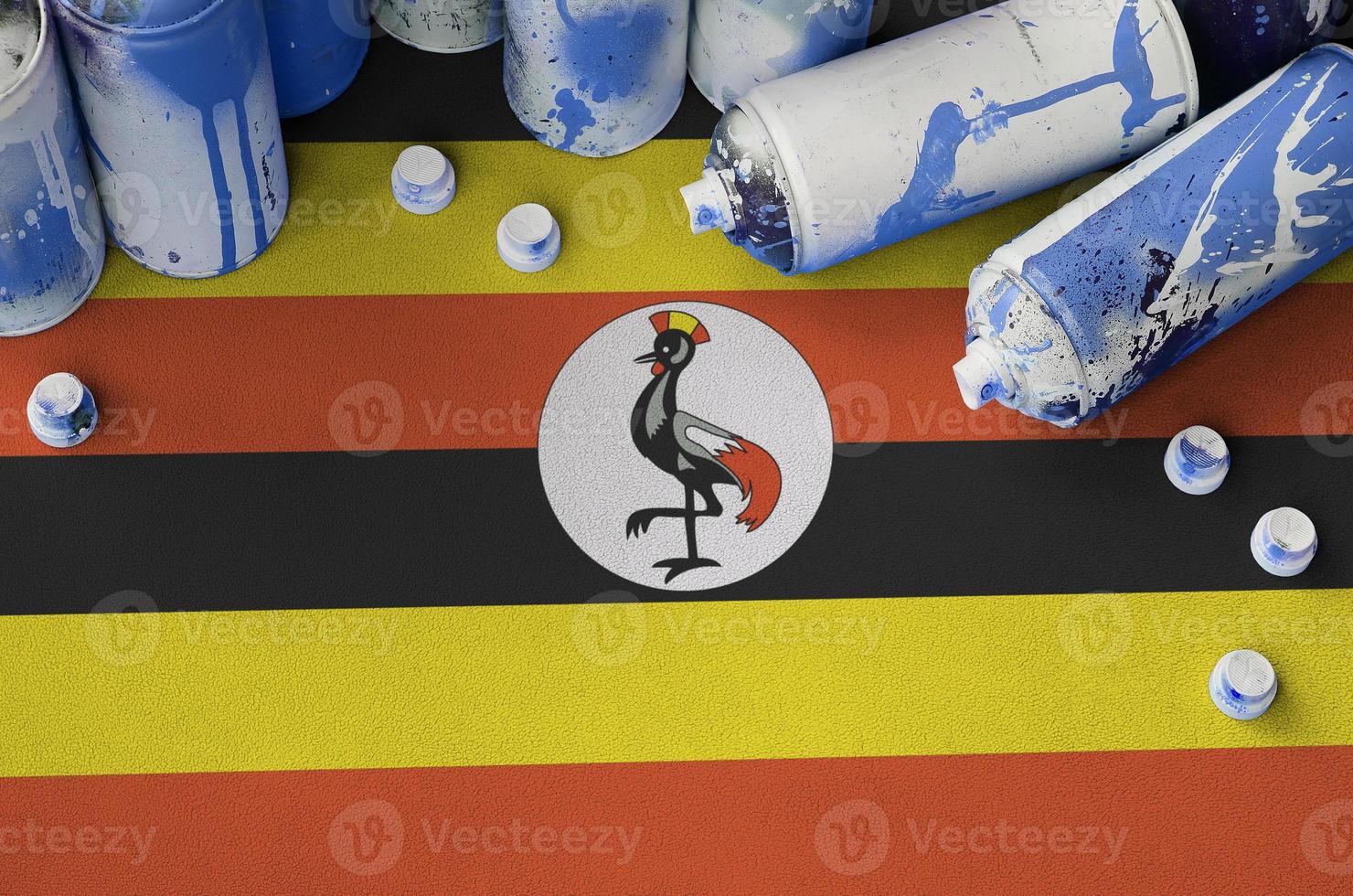 Uganda flag and few used aerosol spray cans for graffiti painting. Street art culture concept photo