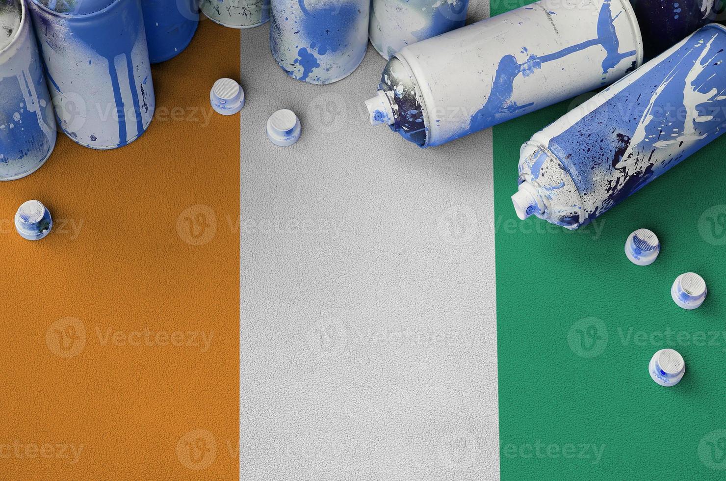 Ivory Coast flag and few used aerosol spray cans for graffiti painting. Street art culture concept photo