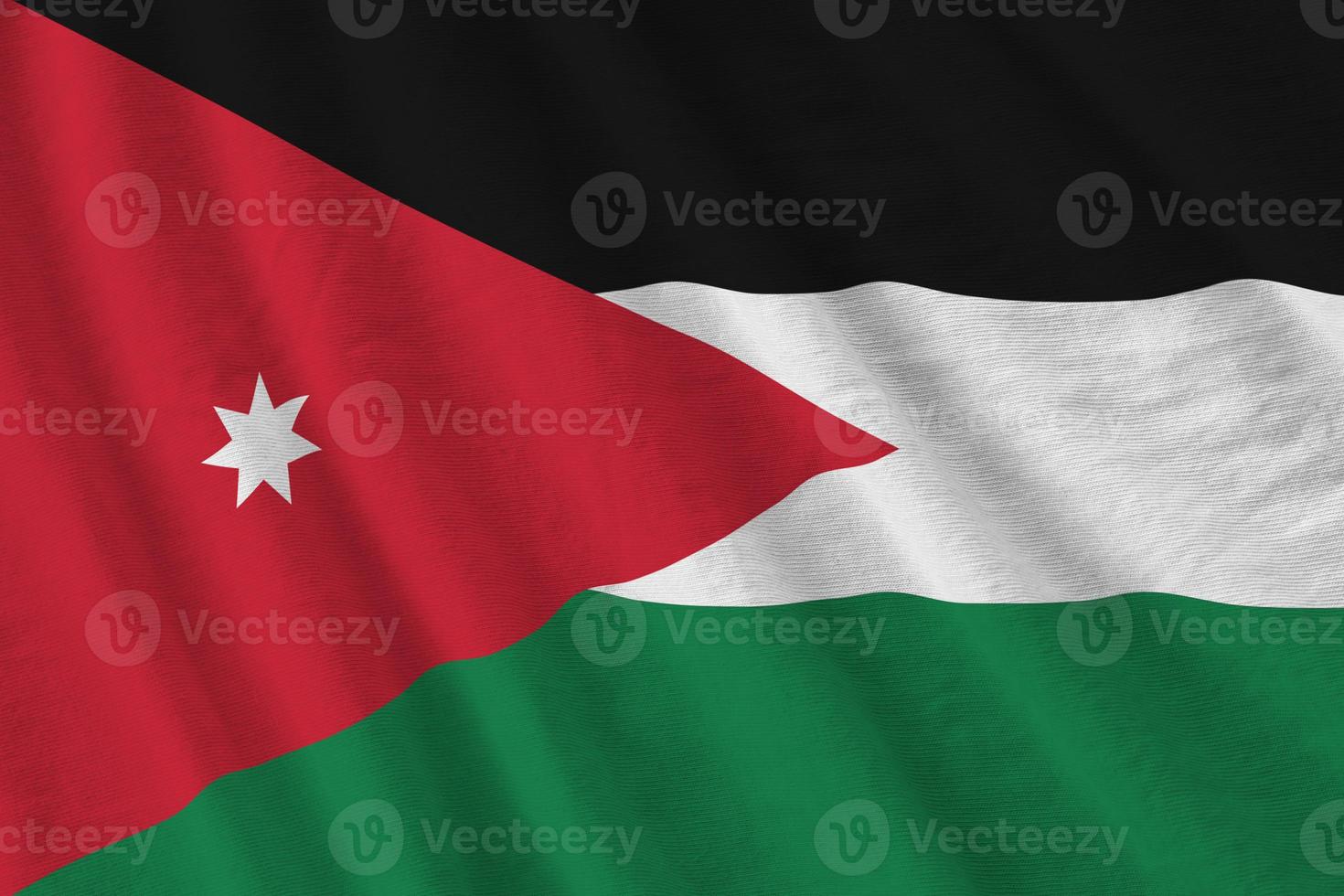 bandera jordana con grandes pliegues ondeando de cerca bajo la luz del estudio en el interior. los símbolos y colores oficiales en banner foto