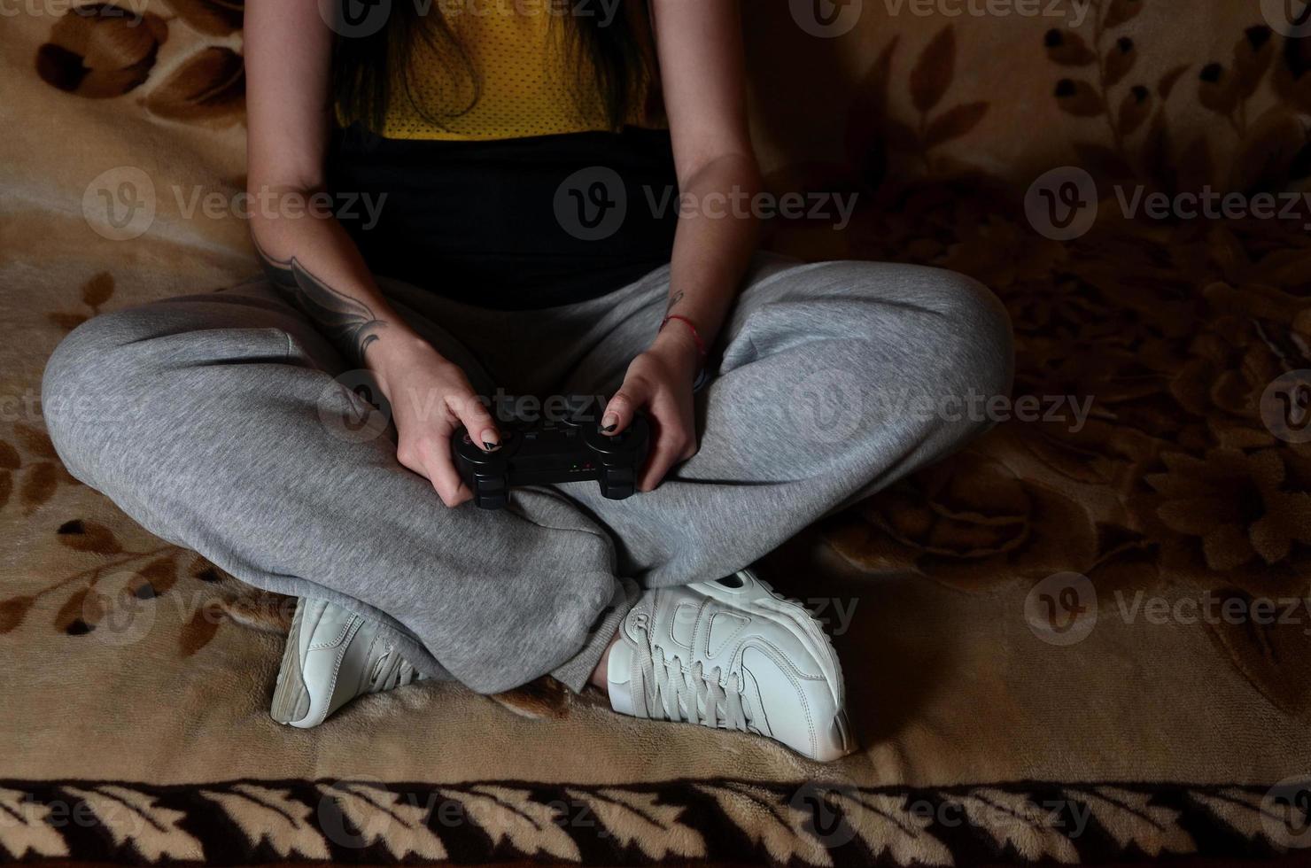 A young girl plays video games with a black joystick with many b photo