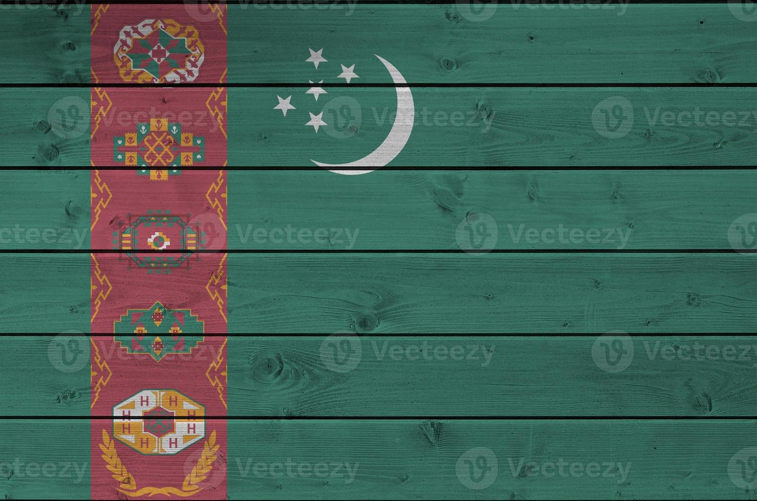 Turkmenistan flag depicted in bright paint colors on old wooden wall. Textured banner on rough background photo