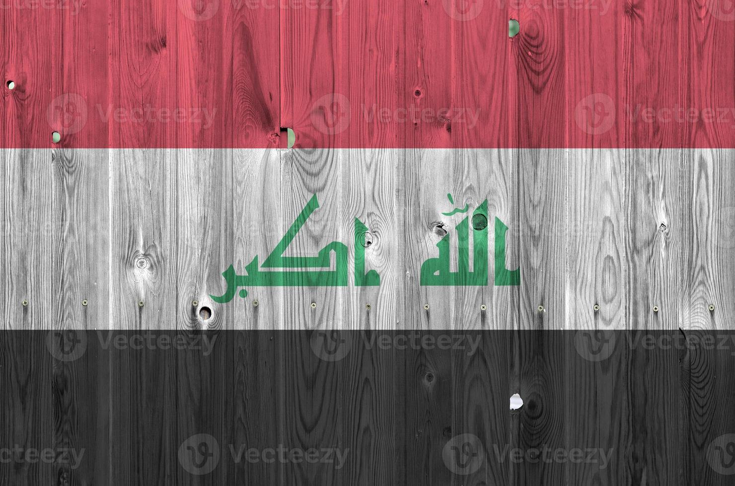 Iraq flag depicted in bright paint colors on old wooden wall. Textured banner on rough background photo