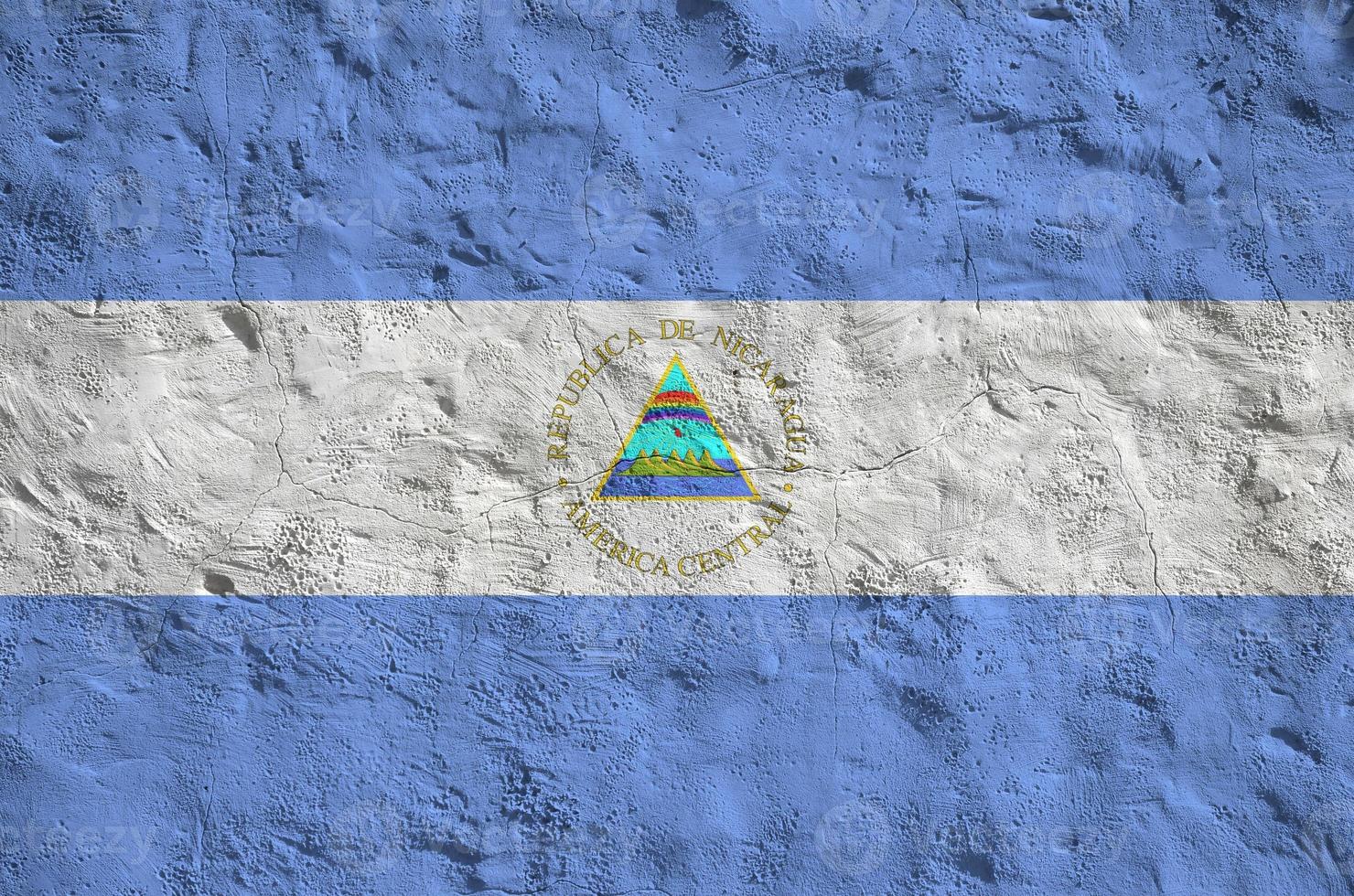Nicaragua flag depicted in bright paint colors on old relief plastering wall. Textured banner on rough background photo