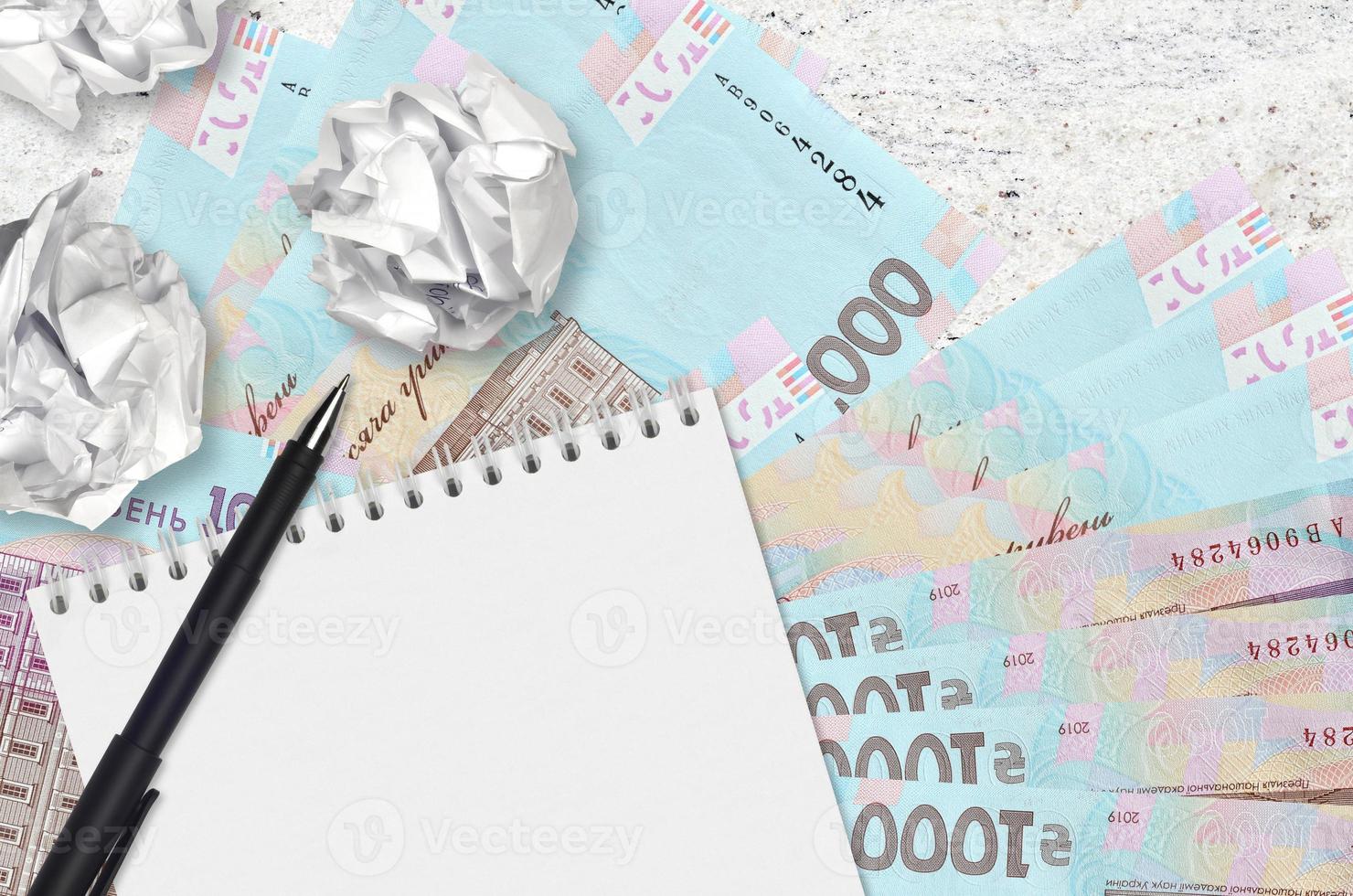 1000 Ukrainian hryvnias bills and balls of crumpled paper with blank notepad. Bad ideas or less of inspiration concept. Searching ideas for investment photo