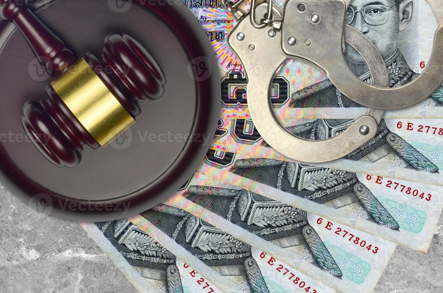 50 Thai Baht bills and judge hammer with police handcuffs on court desk. Concept of judicial trial or bribery. Tax avoidance photo
