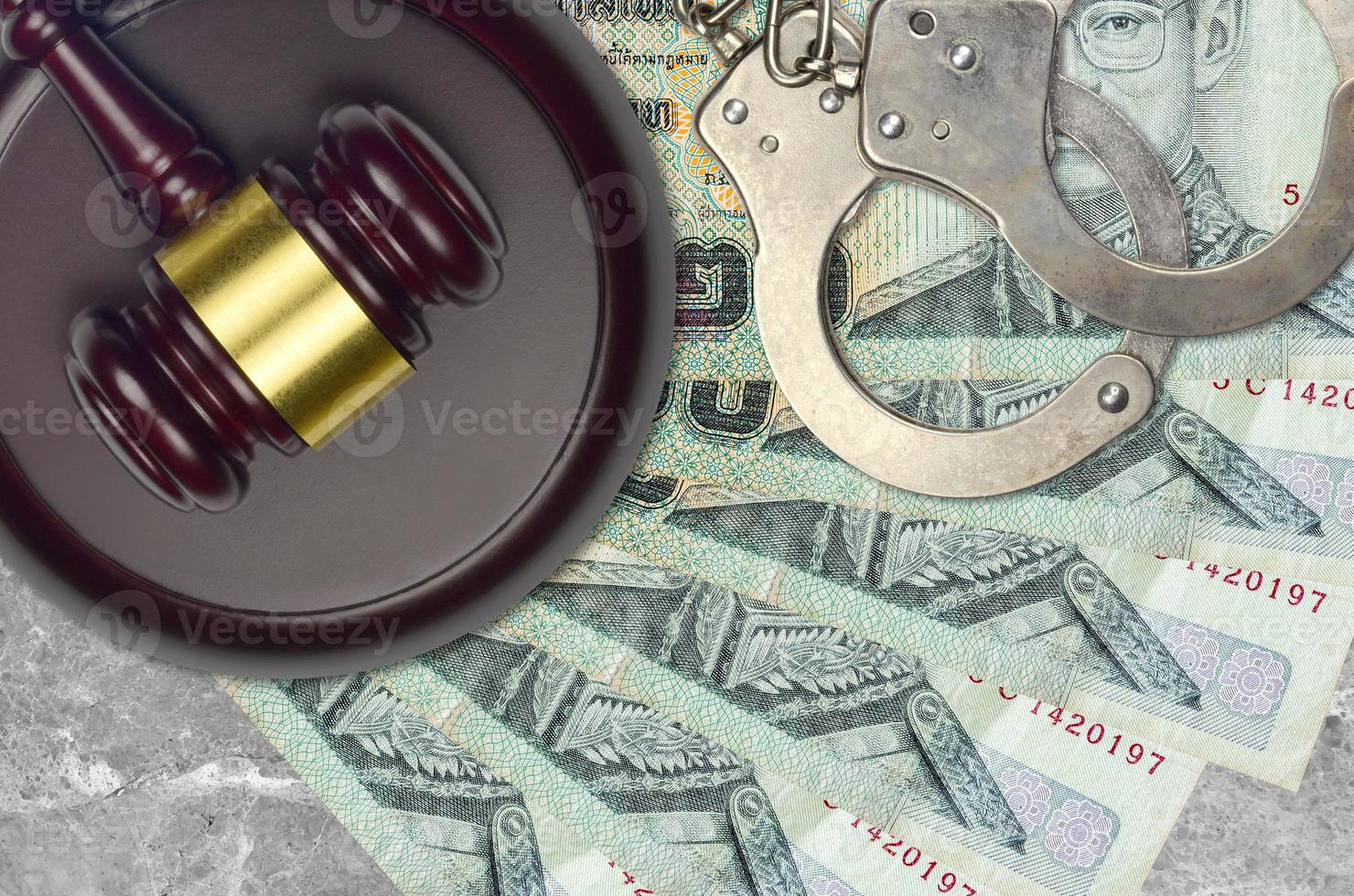 20 Thai Baht bills and judge hammer with police handcuffs on court desk. Concept of judicial trial or bribery. Tax avoidance photo
