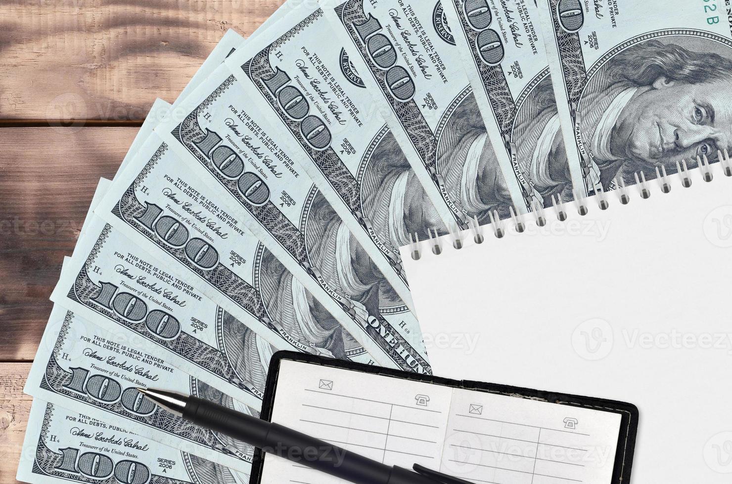 100 US dollars bills fan and notepad with contact book and black pen. Concept of financial planning and business strategy photo