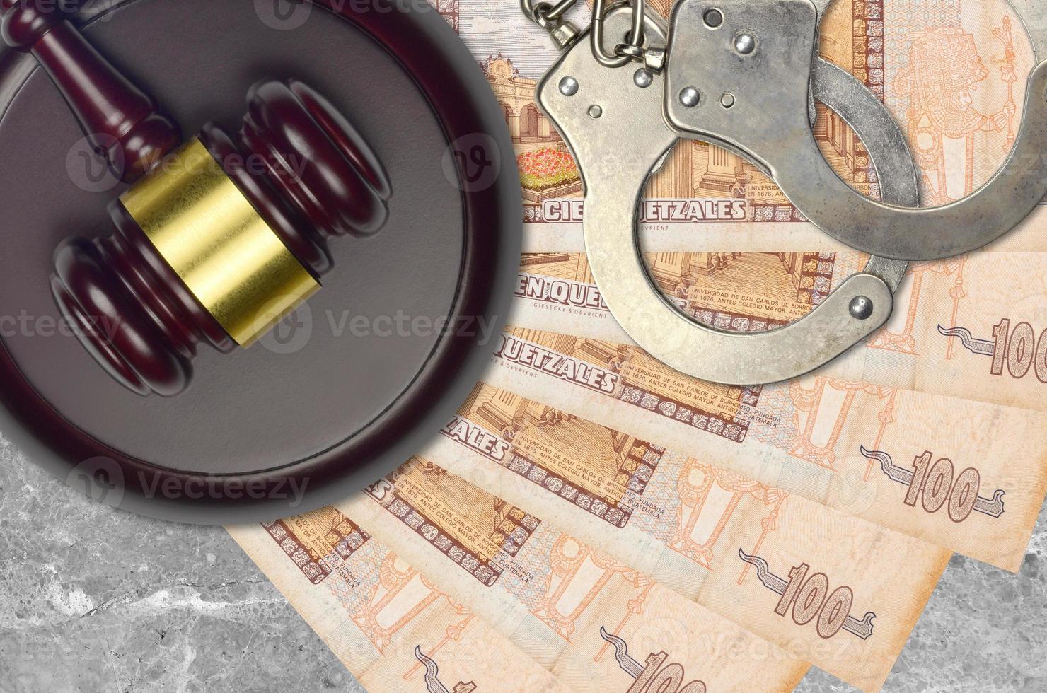 100 Guatemalan quetzales bills and judge hammer with police handcuffs on court desk. Concept of judicial trial or bribery. Tax avoidance photo