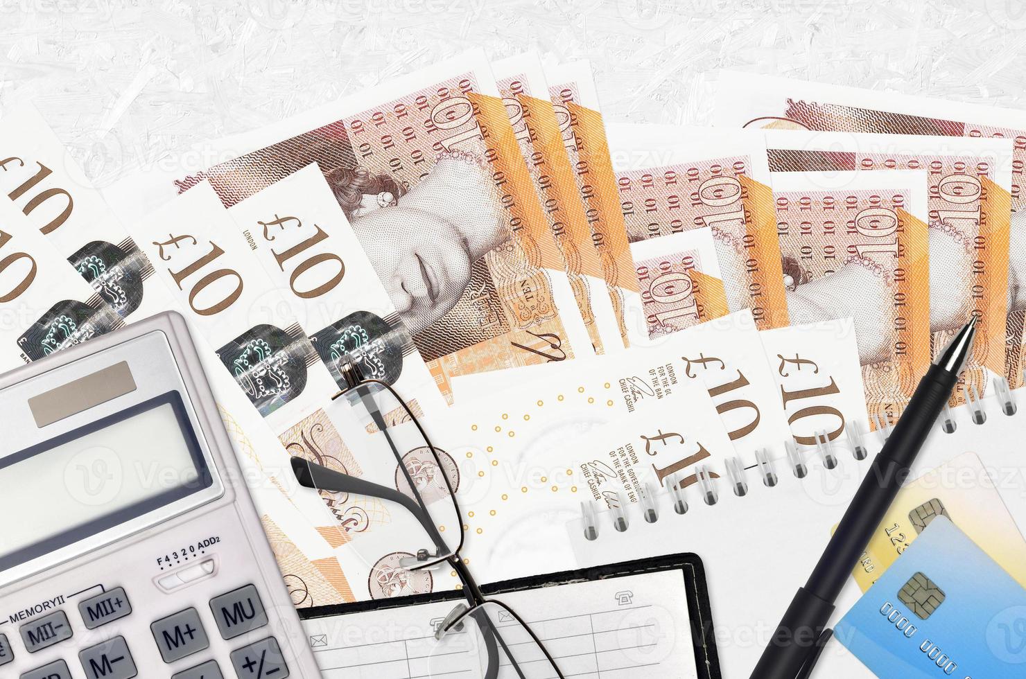 10 British pounds bills and calculator with glasses and pen. Tax payment concept or investment solutions. Financial planning or accountant paperwork photo