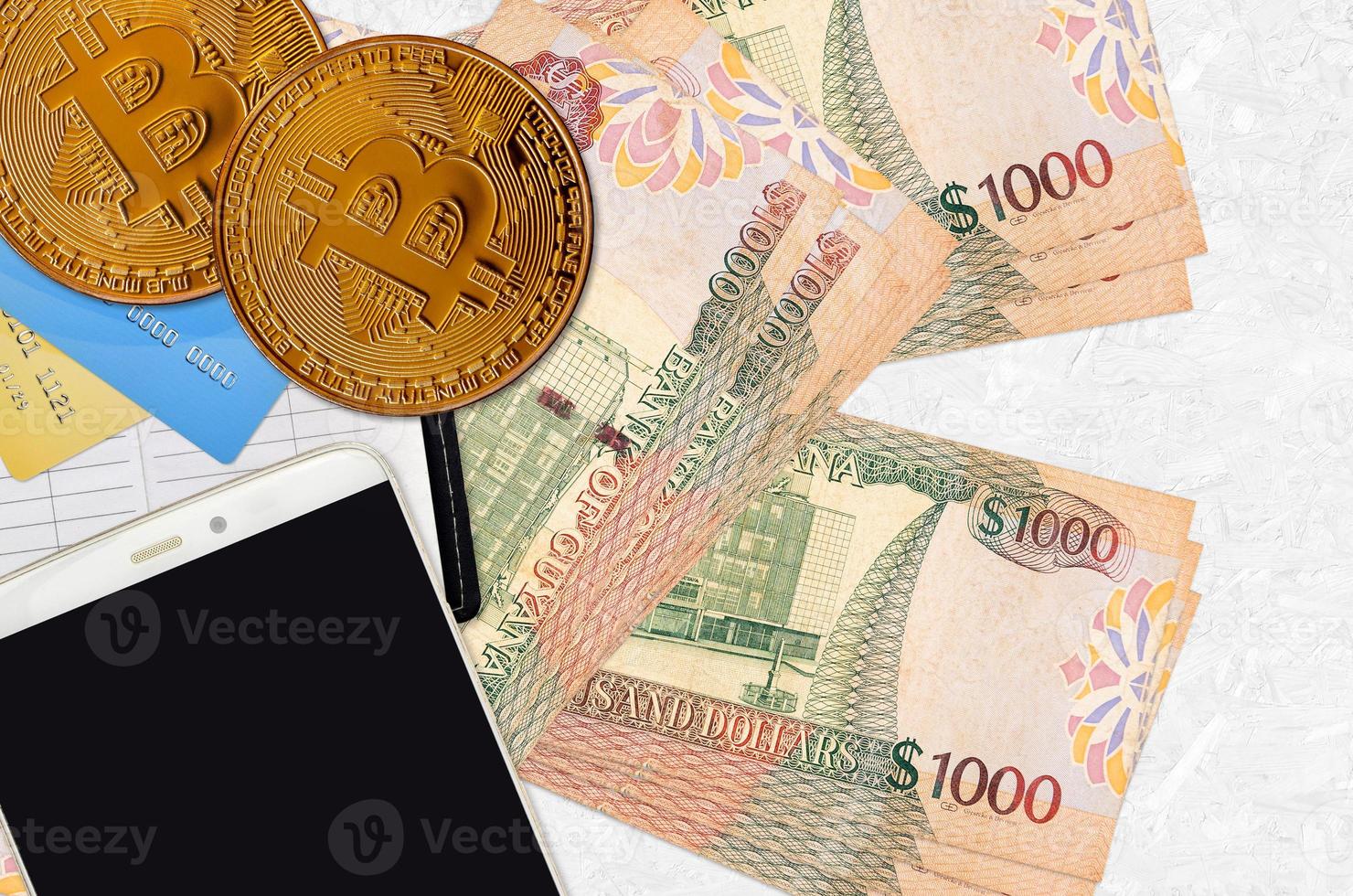 1000 Guyanese dollars bills and golden bitcoins with smartphone and credit cards. Cryptocurrency investment concept. Crypto mining or trading photo