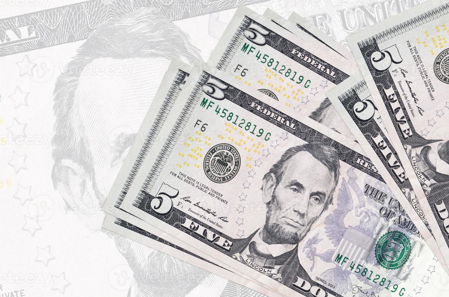 5 US Dollars Bills Lies In Stack On Background Of Big Semi transparent 5-us-dollars-bills-lies-in-stack-on-background-of-big-semi-transparent
