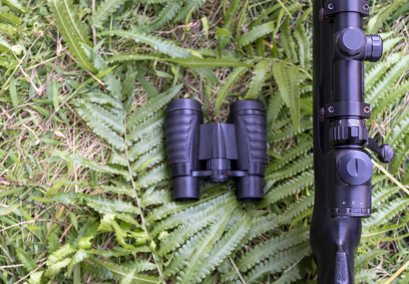 binoculares de vista superior y rifle en el suelo de hierba foto