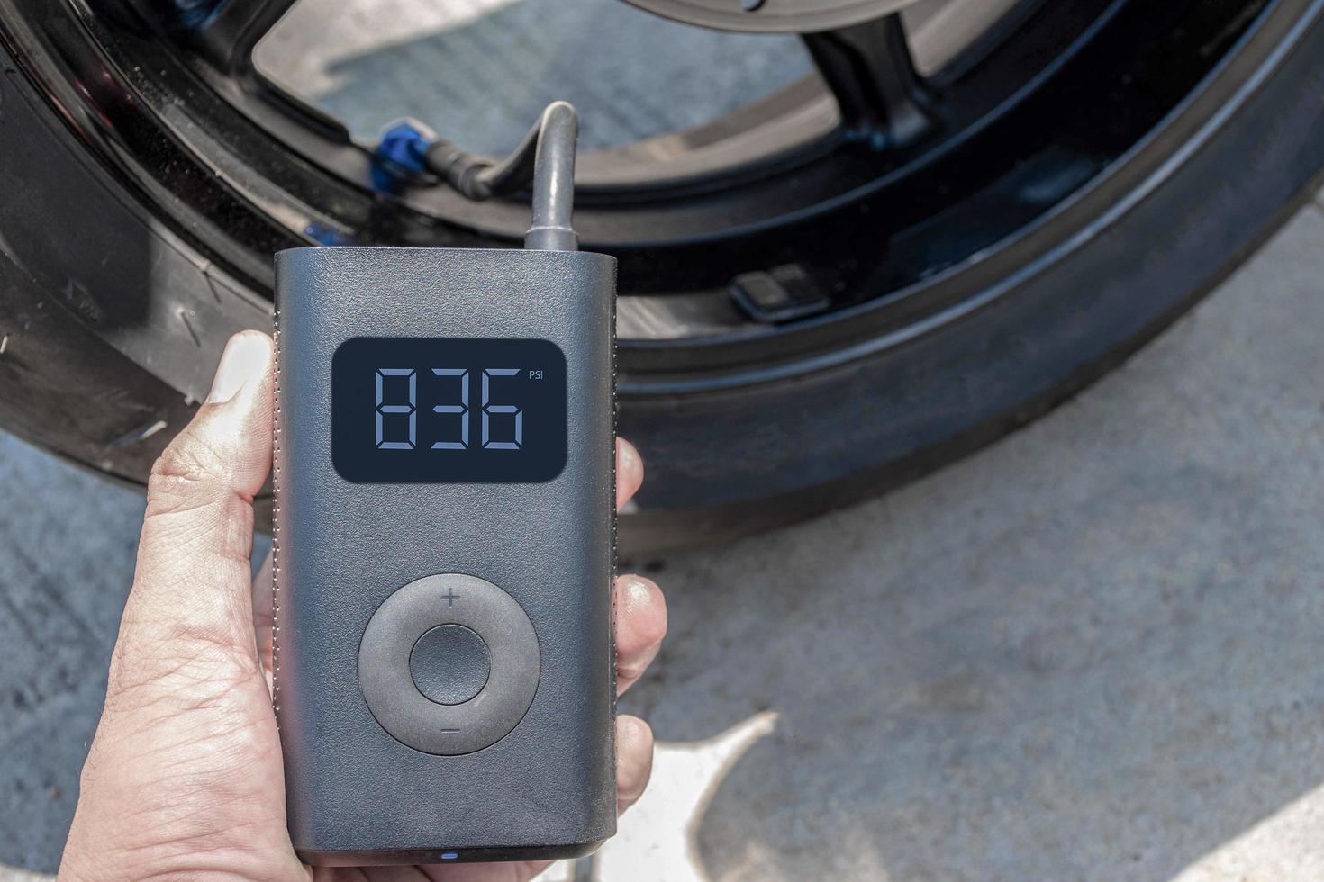 Hand holding a portable inflator is inflating a motorcycle tire. photo