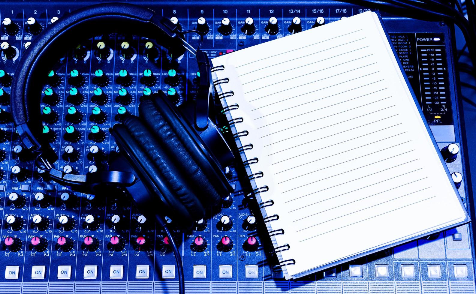 Top view black headphone and notebook on console sound board mixer photo