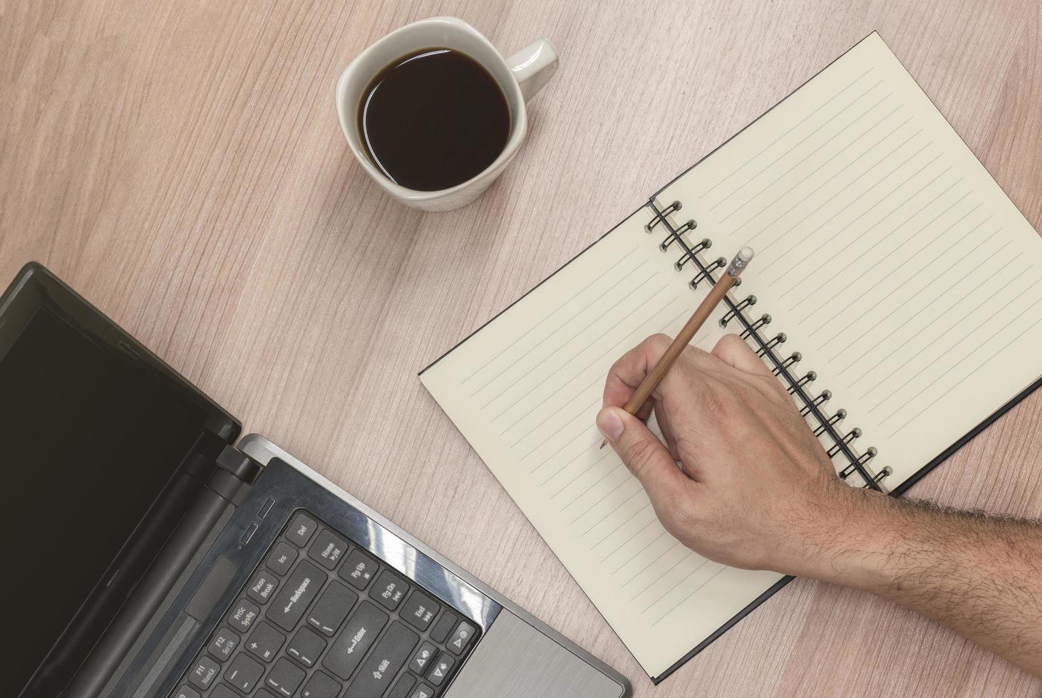 Businessman hand holding pen to take note on notebook with laptop display show slide presentation photo