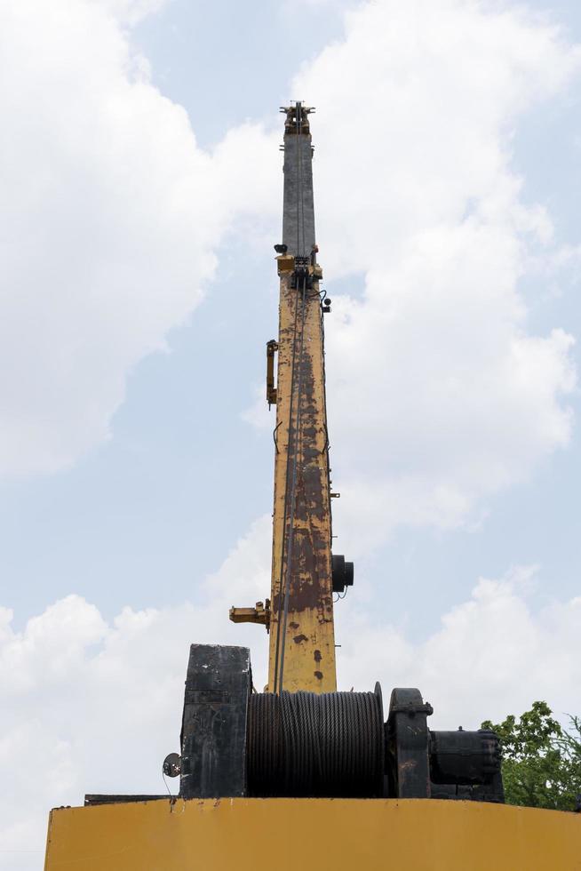 Yellow crane boom with hooks and blue sky background photo