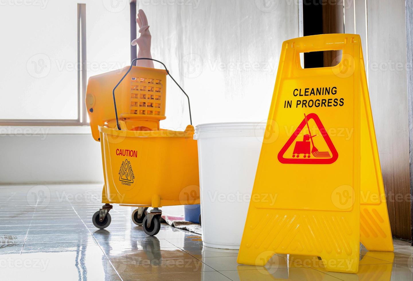 Close up yellow warning sign with message Cleaning in progress with cleaning trolley background photo