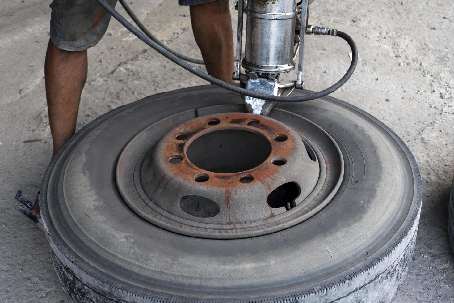 Mechanic is using a tool to remove tires from truck wheels. photo