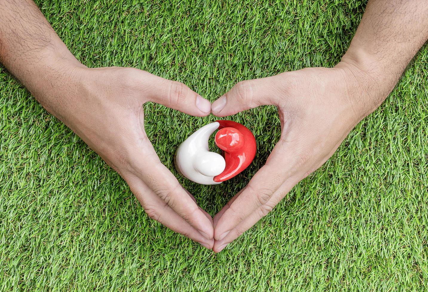 Top view mock up couple hugging on grass floor with in hand heart symbol. Valentine day concept photo