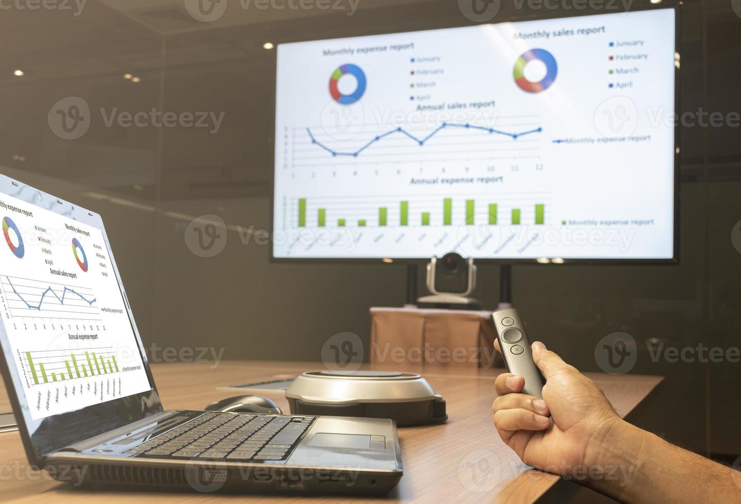 Businessman hand hold remote control slide with presentation on display laptop and television photo