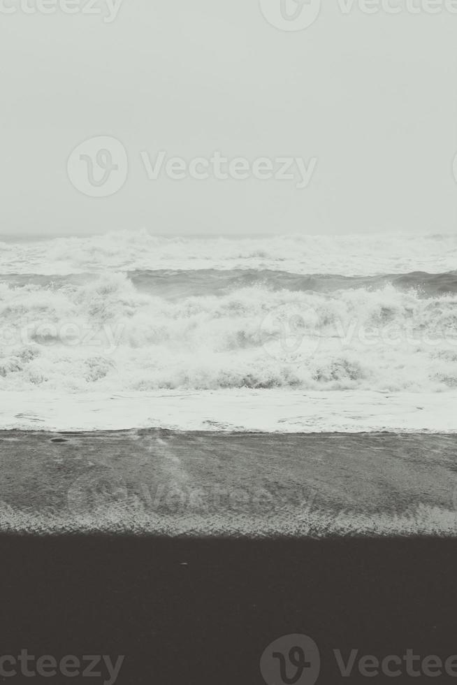 Foamy waves on black beach monochrome landscape photo