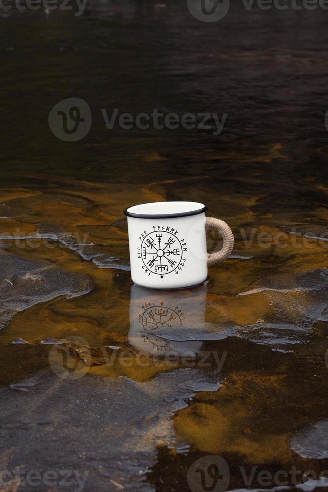 Close up cup with runes on wet beach concept photo